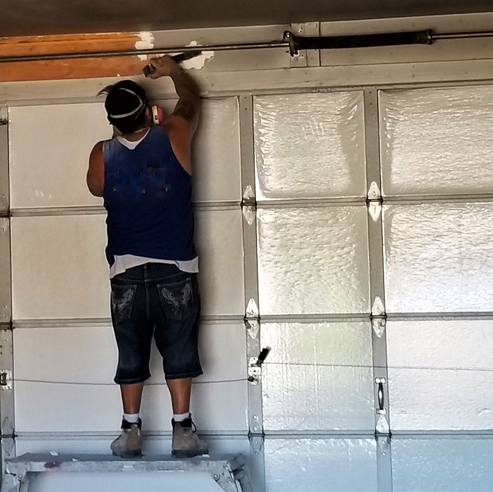 Technician repairing a garage door for Expert Garage Doors.