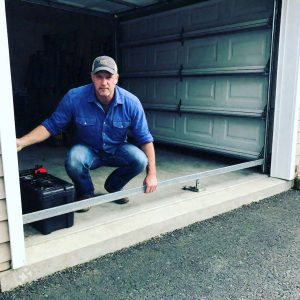 Technician fixing garage door hardware for Expert Garage Doors.