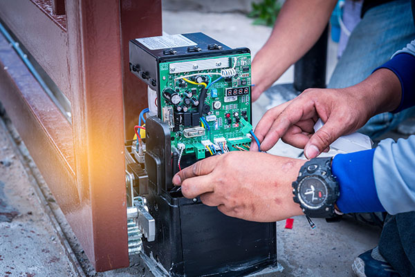 A team of technicians from Expert Garage Doors repairing a gate motor.