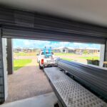 Bakkie towing a trailer near roller shutter doors installed by Expert Garage Doors.