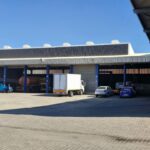Trucks and cars parked outside warehouse with roller shutter doors by Expert Garage Doors.
