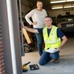 Expert Garage Doors technician discussing garage door work with happy homeowner.