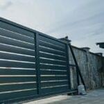 Black gate with motor system installed by Expert Garage Doors.