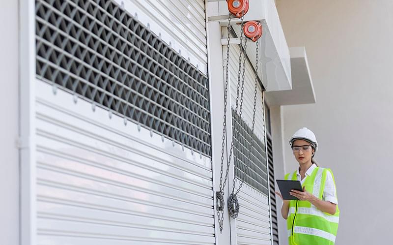 Woman inspecting roller shutter doors installed by Expert Garage Doors.