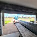 Bakkie towing a trailer near roller shutter doors installed by Expert Garage Doors.